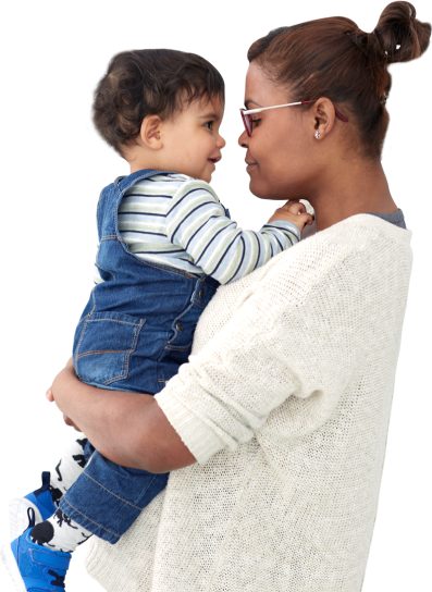 Caring nanny smiling as she gently holds toddler sporting overalls