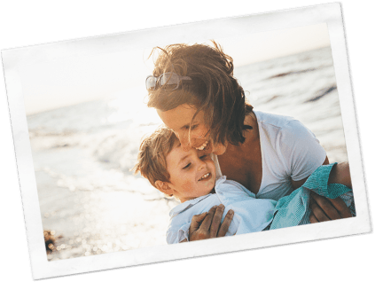 Photograph of a laughing woman holding a toddler at the beach