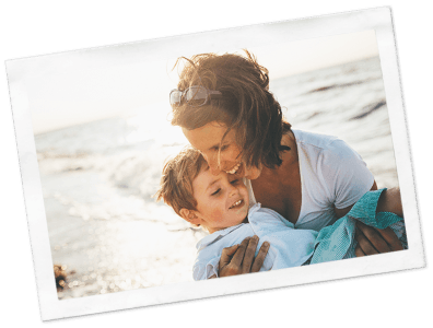 Woman laughing as she holds a toddler at a beach
