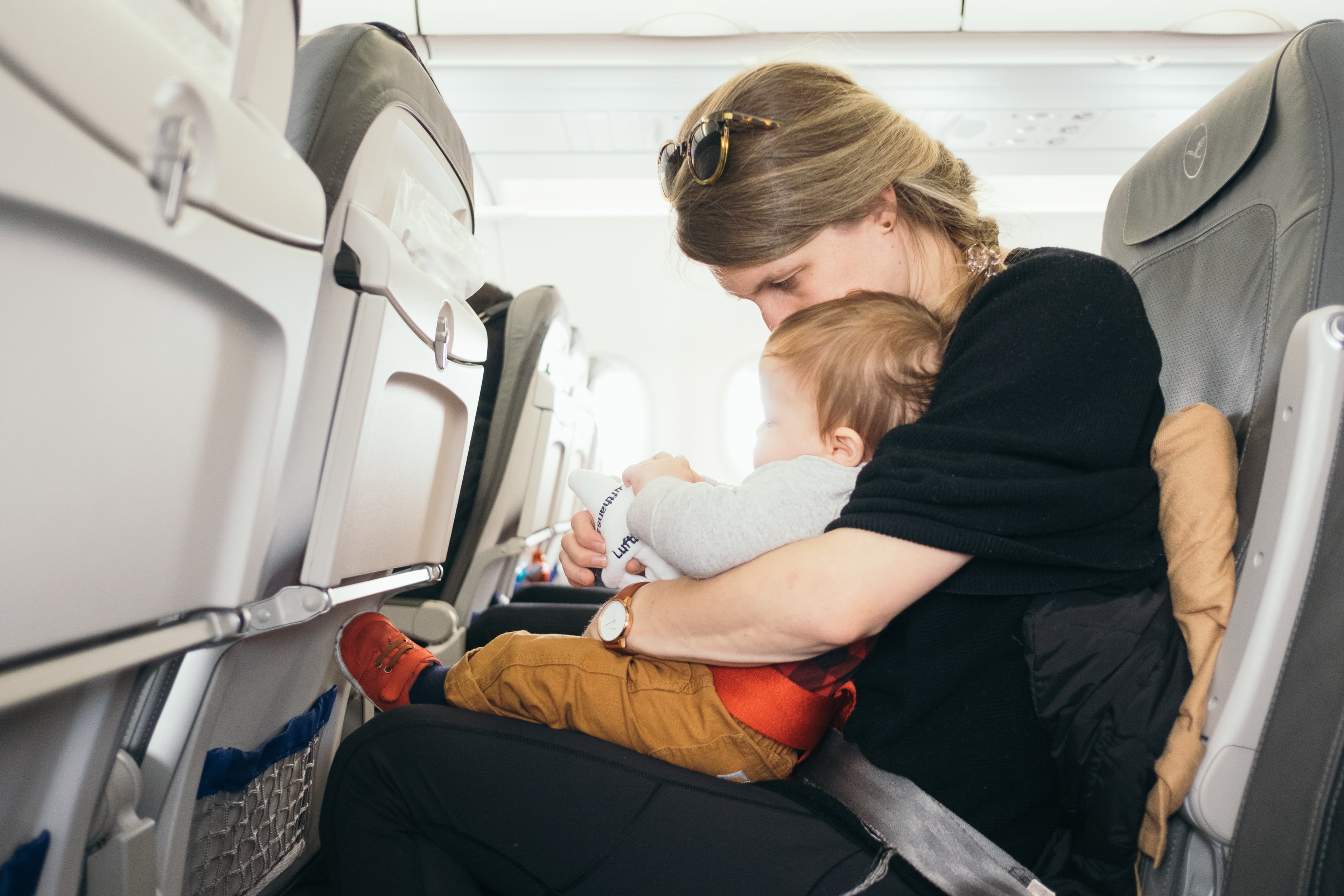 A woman sitting on a plane with a child on her lap