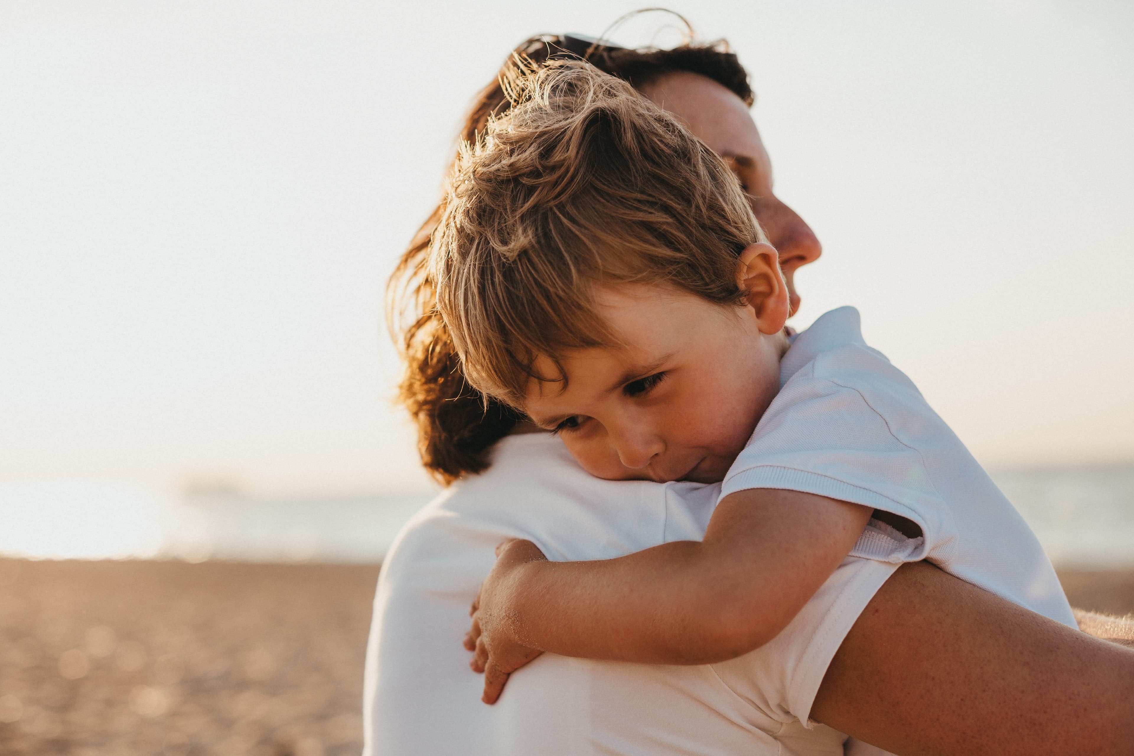 A child hugging an adult on the beach