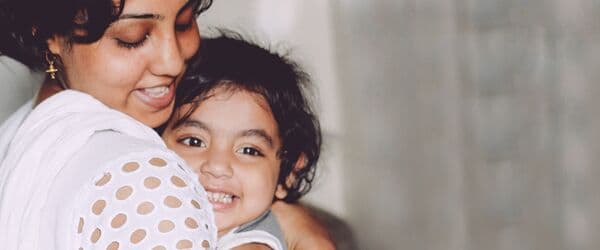 Woman hugging a smiling child close to her chest