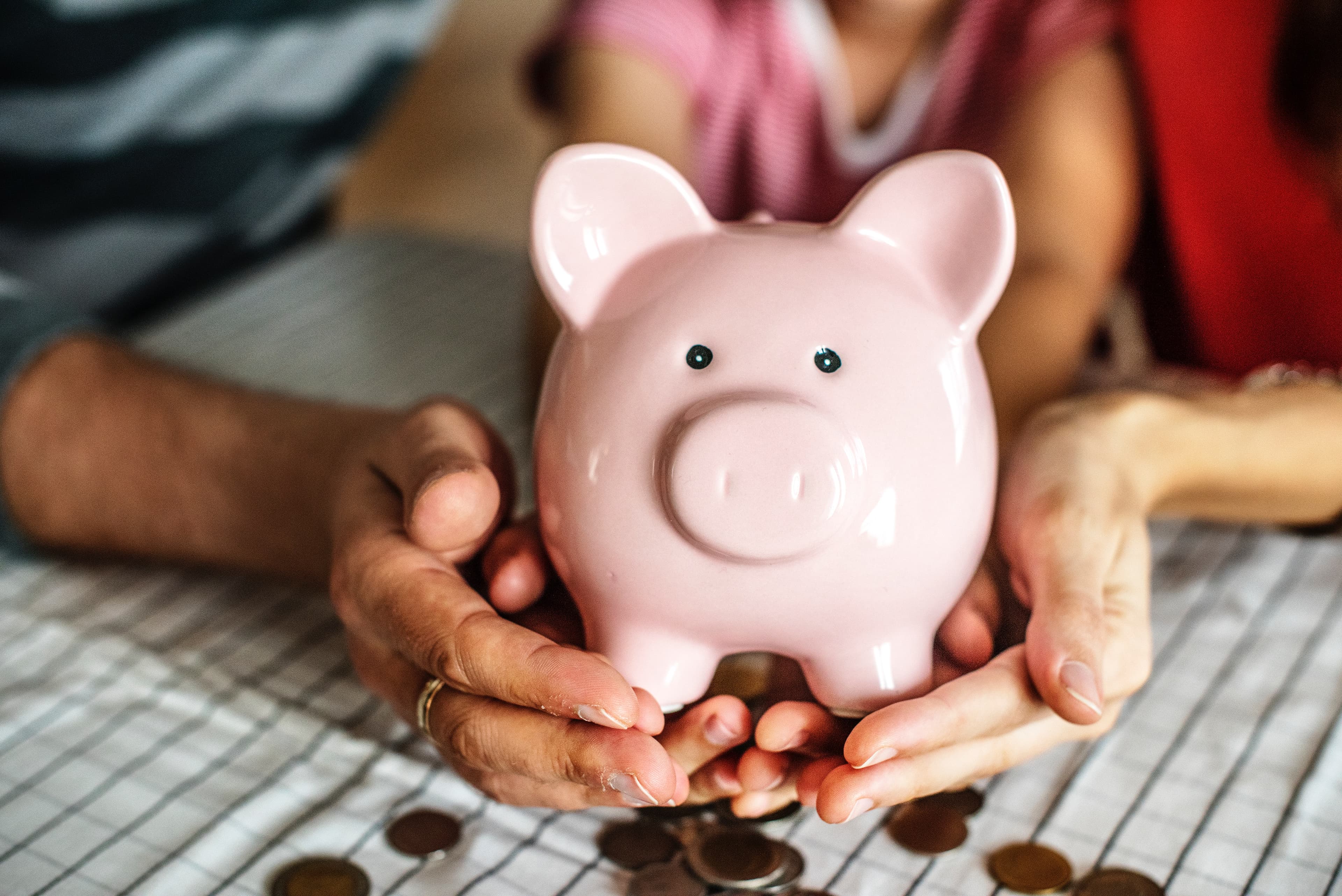A pink ceramic piggy bank held between two hands