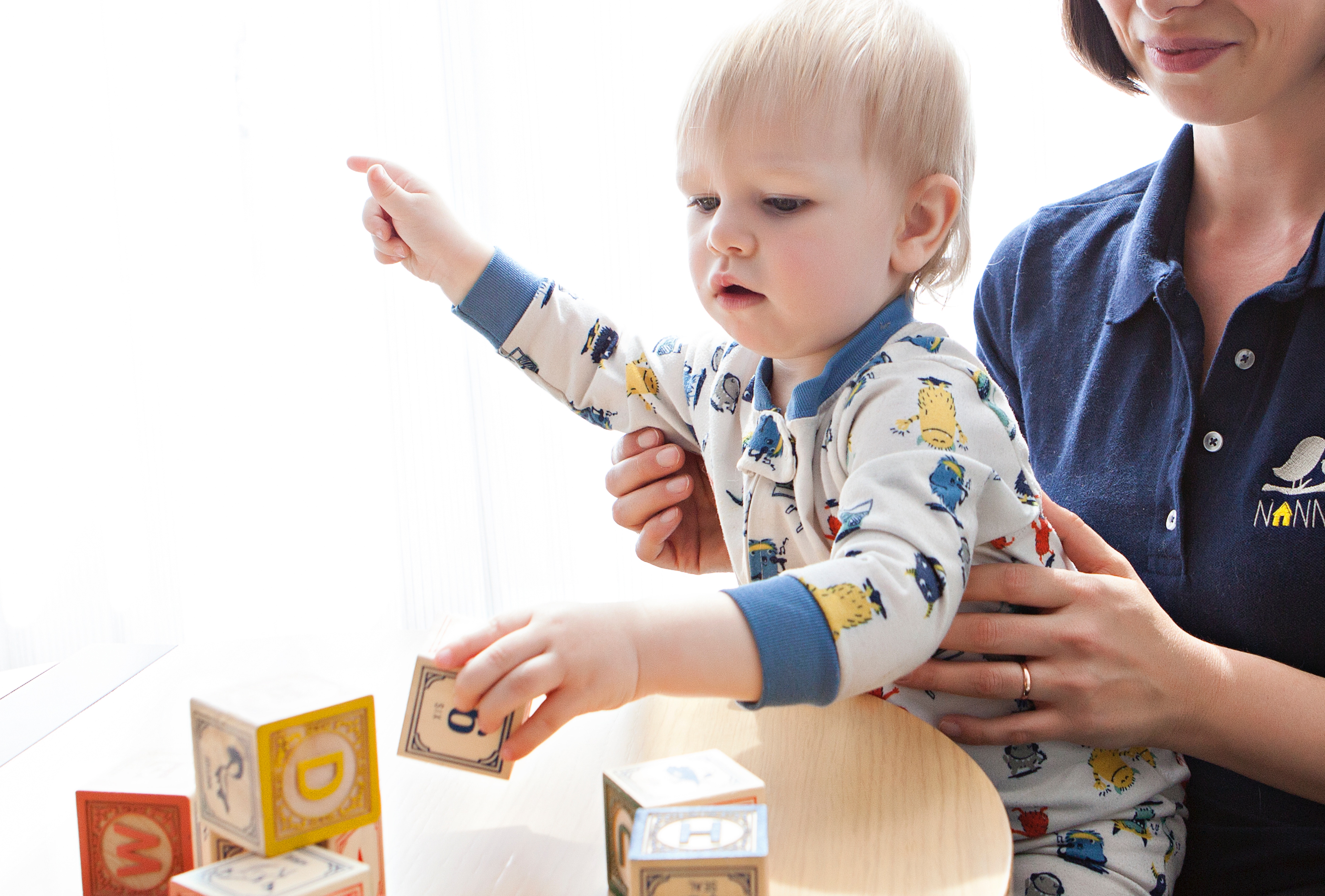 child playing building blocks while held by caregiver