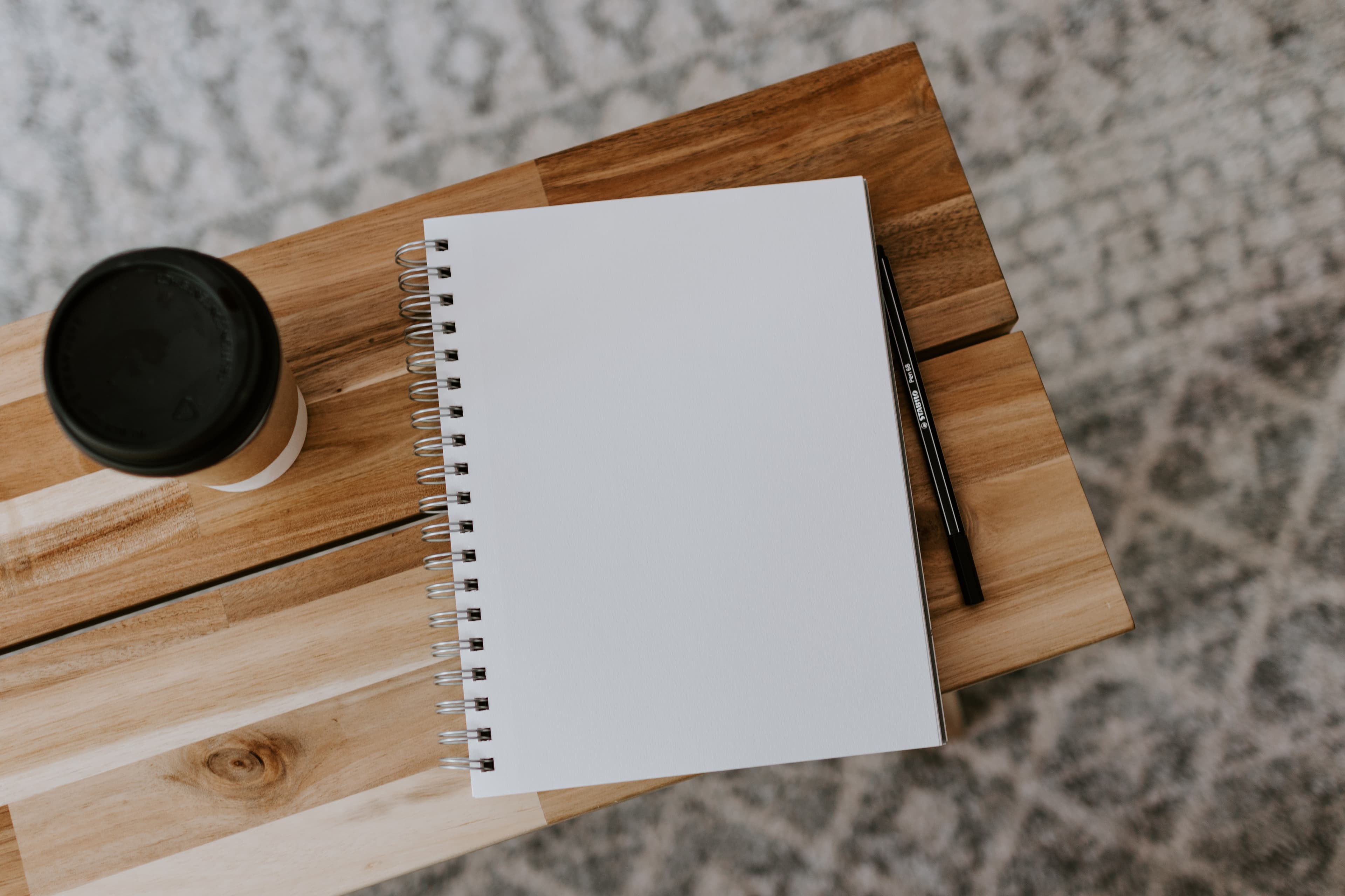 Wooden table with coffee cup and notepad