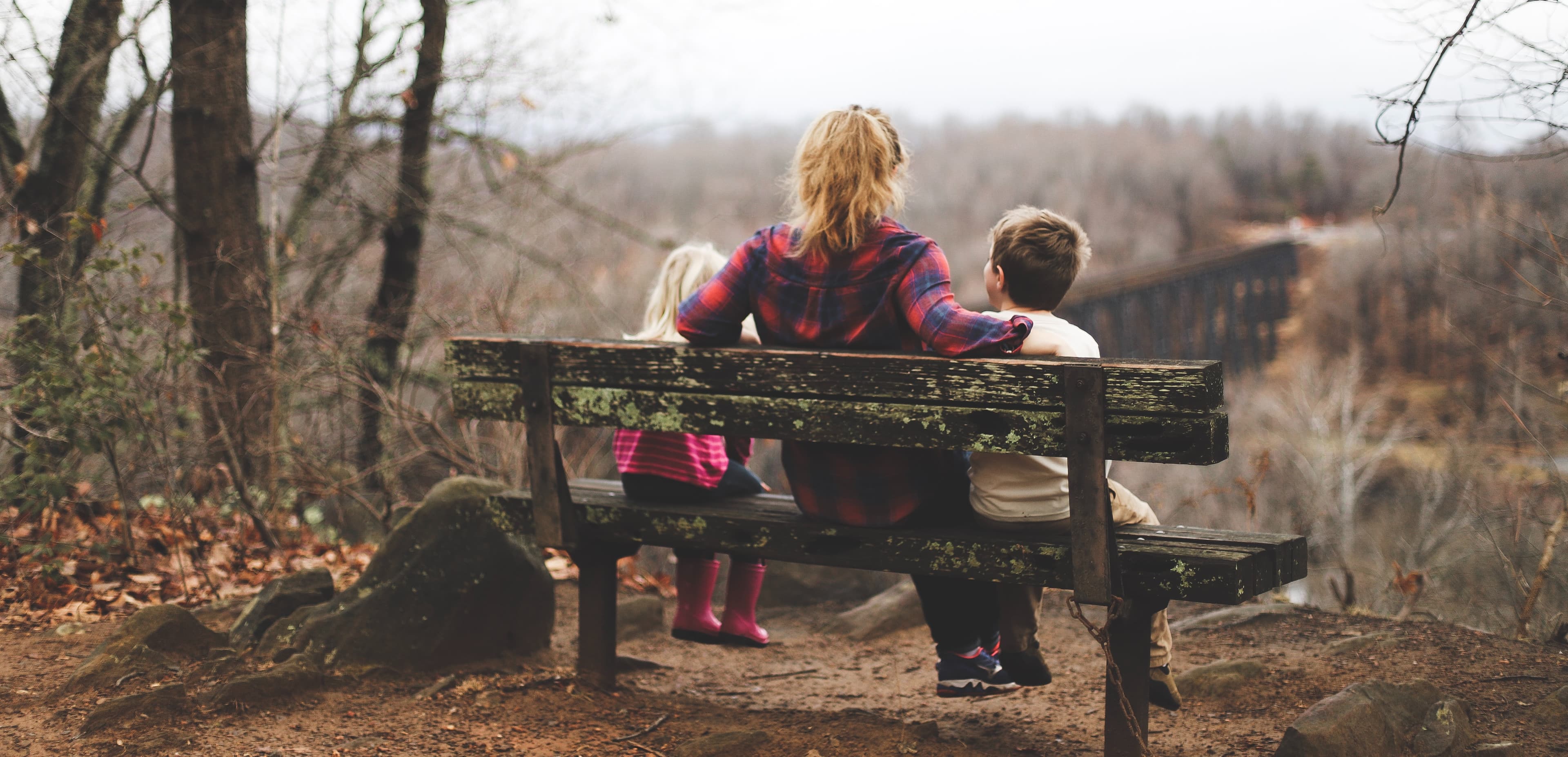 A woman and two children sitting on a bench