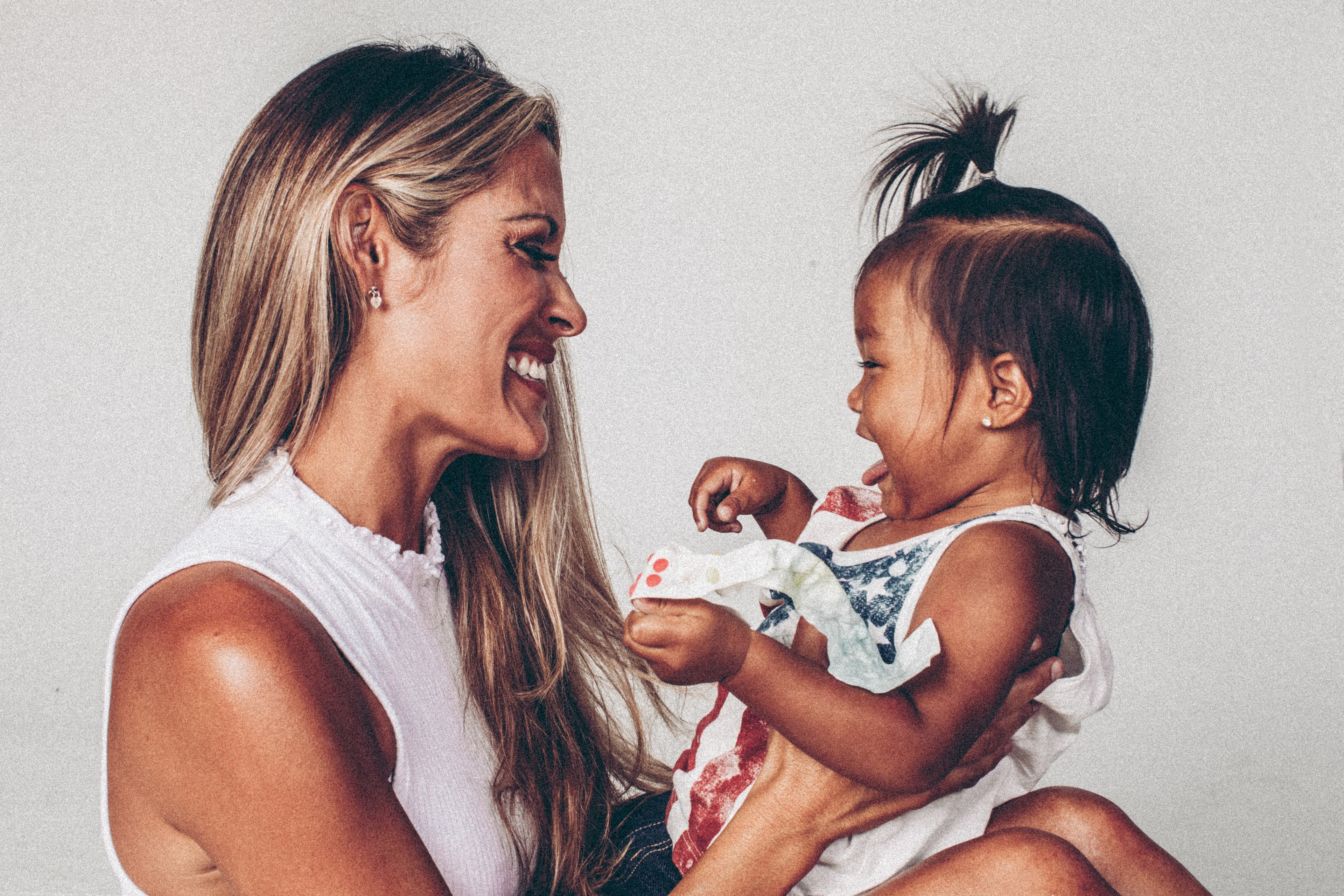 A woman holding a baby in front of her and smiling