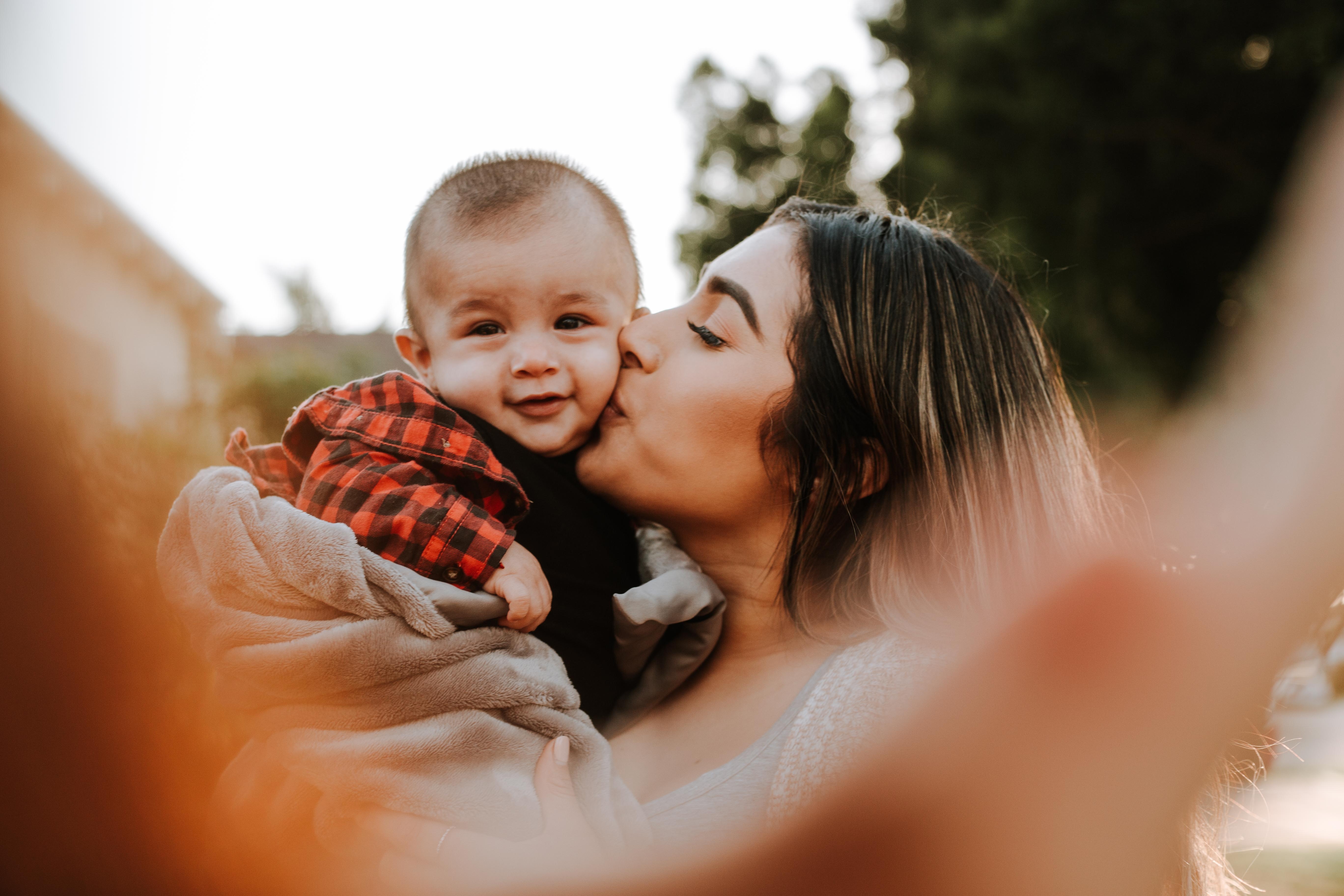A woman kissing a child on the cheek