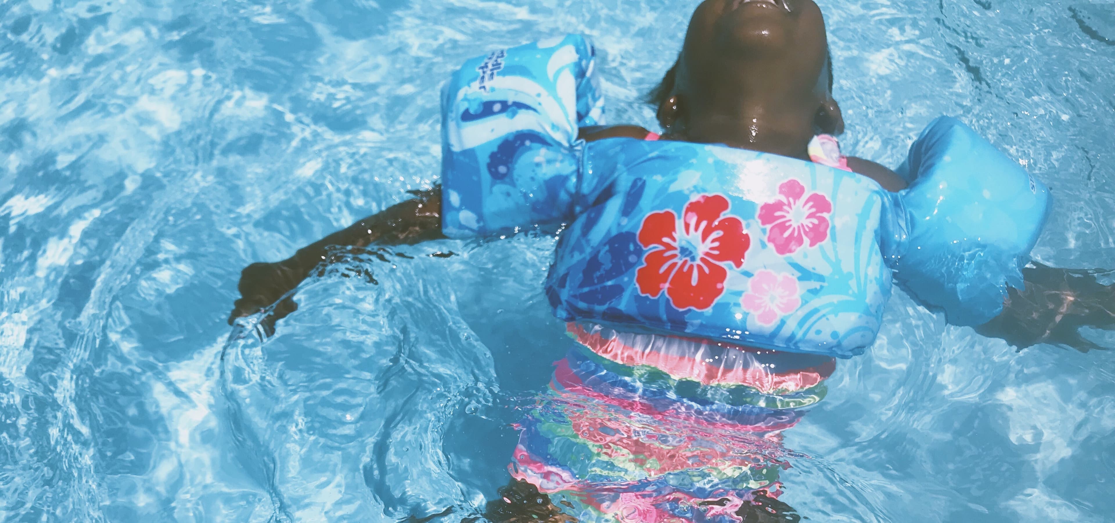 A child with floaties swimming in a pool