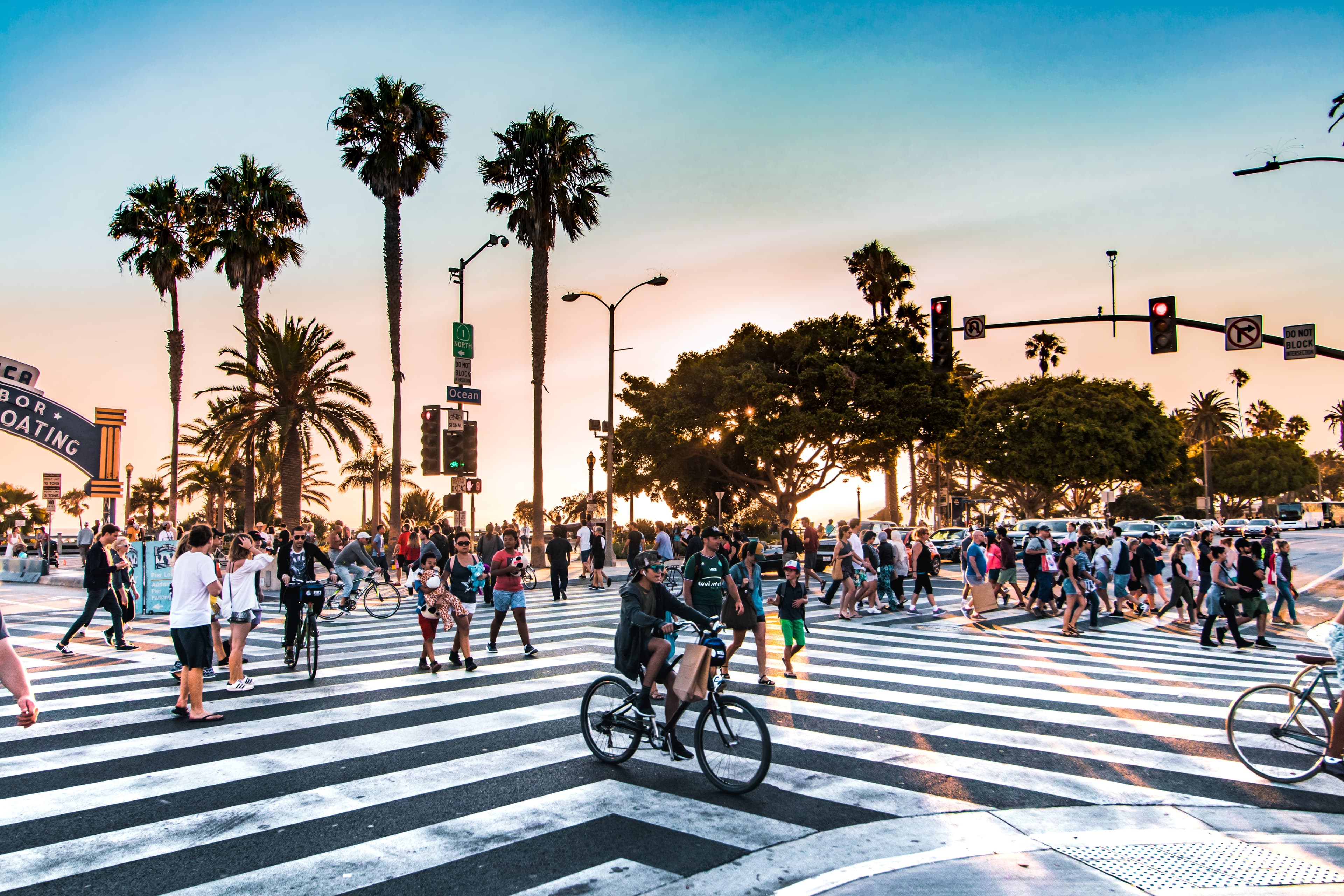 lively intersection in LA with palm trees, bike riders and pedestrians