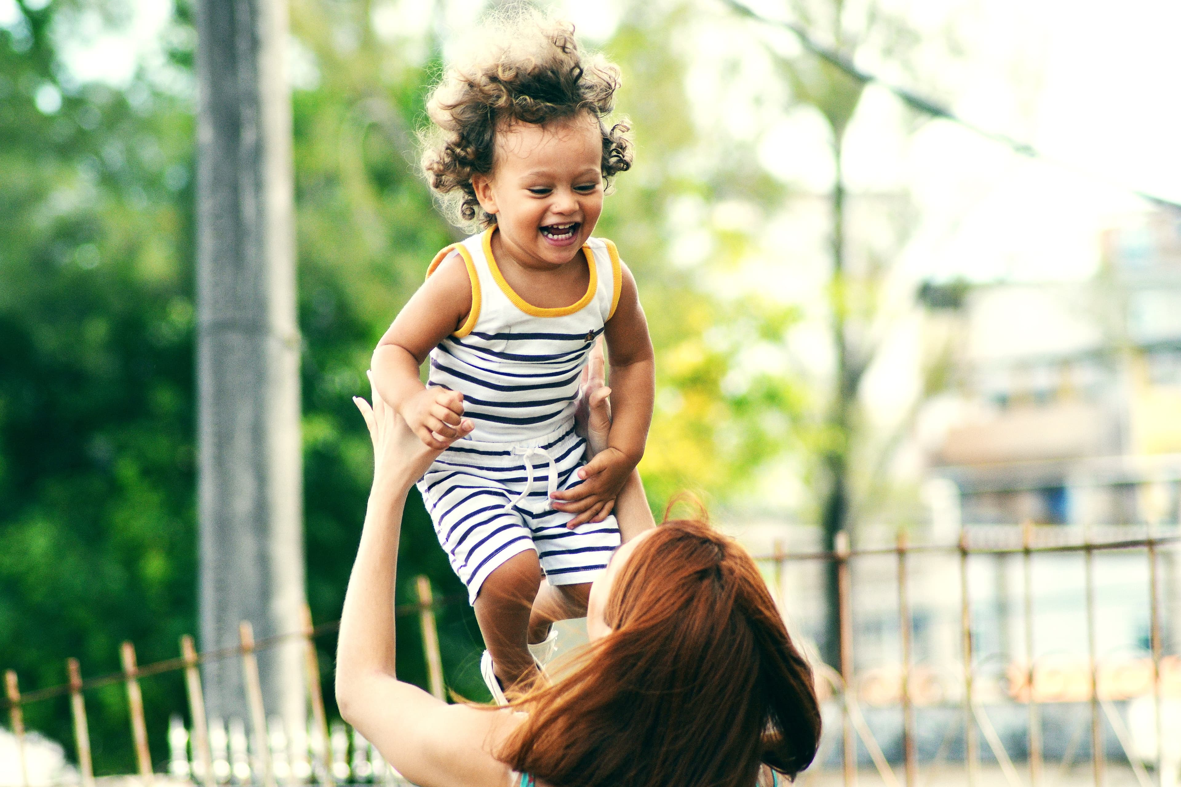 Woman holding up a baby in the air that's smiling